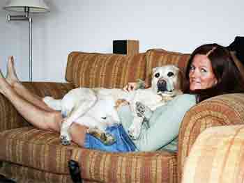 Jane lying on the sofa with one of her dogs lying on top of her having a cuddle